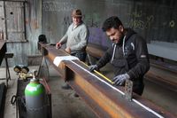 Zwei Männer bearbeiten Stahlträger beim Kulturkosmos in Lärz.
